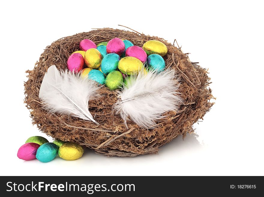 Easter eggs in a natural bird nest with two feathers and scattered, isolated over white background. Easter eggs in a natural bird nest with two feathers and scattered, isolated over white background.