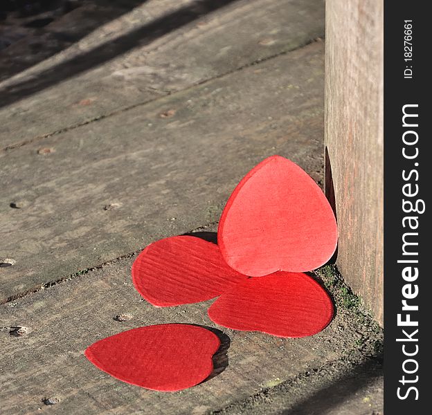 Heart-shaped confetti landed on wood. Heart-shaped confetti landed on wood