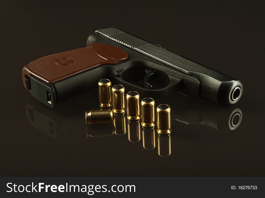 A gun and 7 bullets on a glass table over a dark background. A gun and 7 bullets on a glass table over a dark background