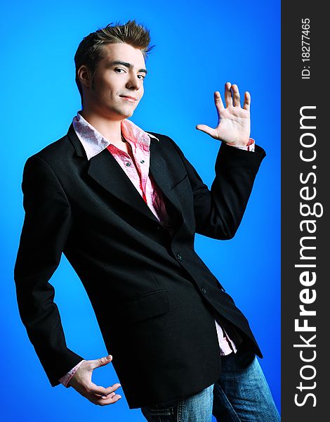 Young man dressed in rock'n'roll style, dancing over blue background. Young man dressed in rock'n'roll style, dancing over blue background.