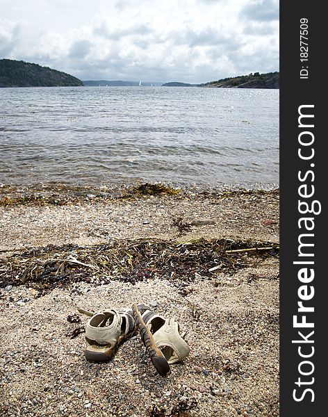 This is a shot of one pair of sandals on the beach. Focus on sandals. background soft focus.