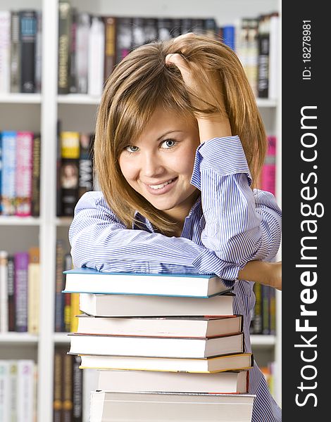 Young smilling woman sitting with books in the library. Young smilling woman sitting with books in the library