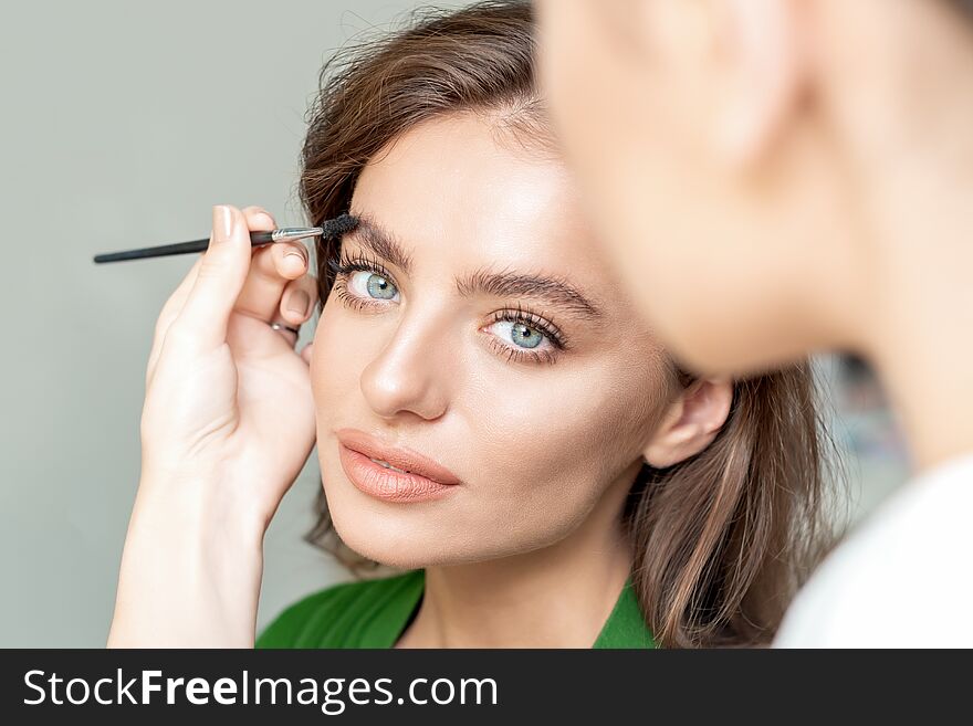 Eyebrows makeup for young women with eyebrow brush tool by makeup artist. Eyebrows makeup for young women with eyebrow brush tool by makeup artist