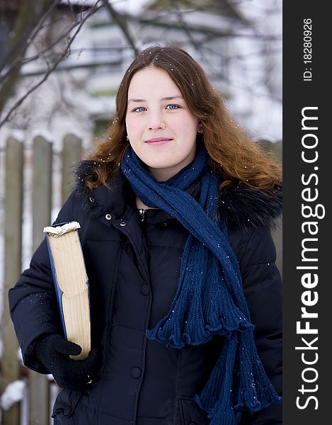 Smiling young girl with book in winter