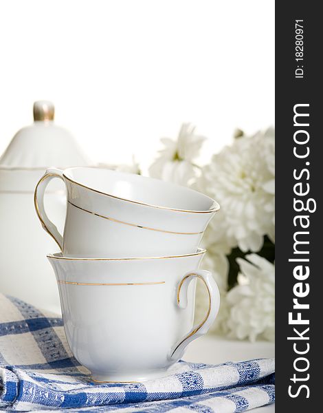 Two teacup on white-blue napkin on table against flowers
