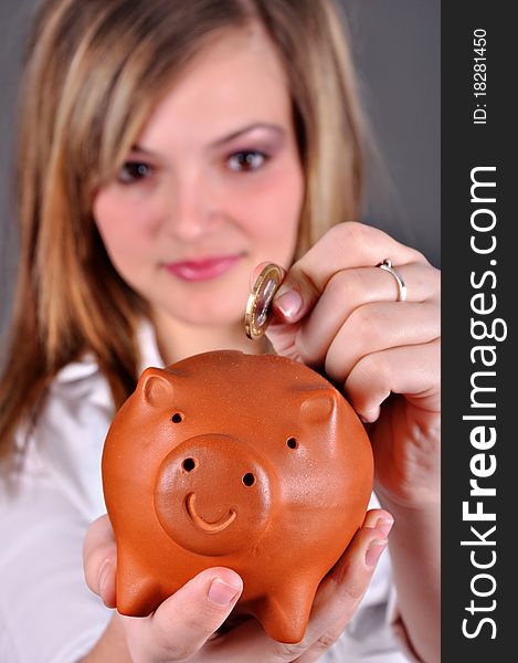Beautiful young girl putting money in her piggy bank