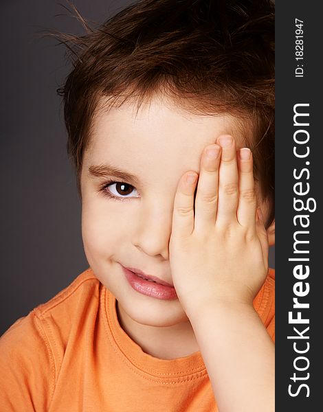 Portrait of cute smiling little boy closed one eye with his hand, studio shot. Portrait of cute smiling little boy closed one eye with his hand, studio shot