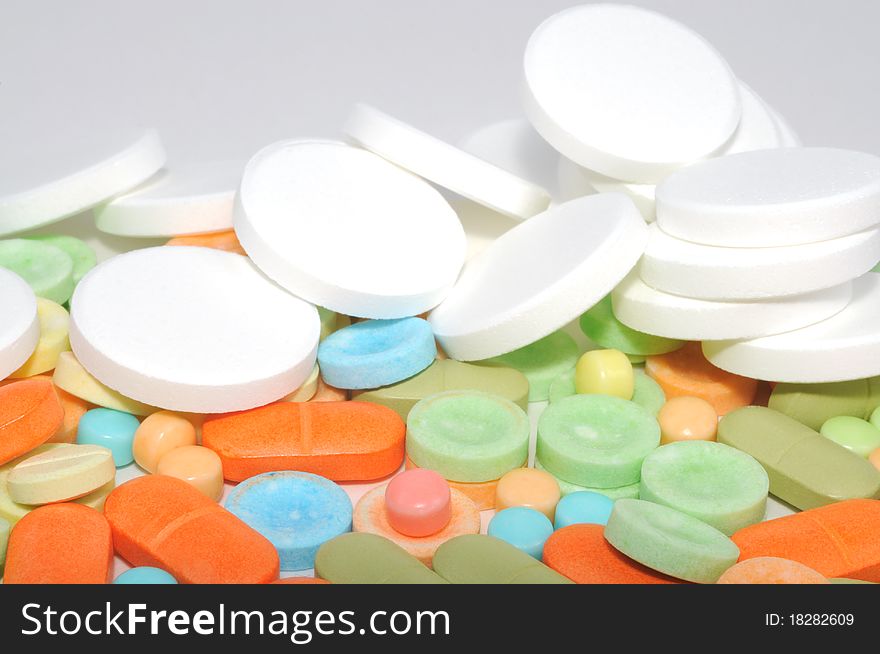 Border from colorful pills on a white background