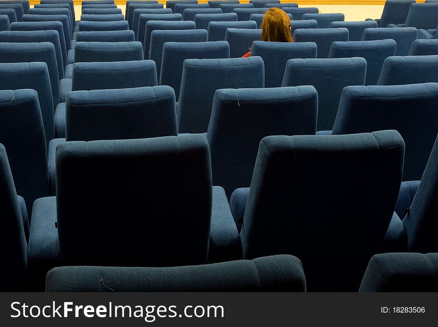 A woman is sitting alone in an empty theater