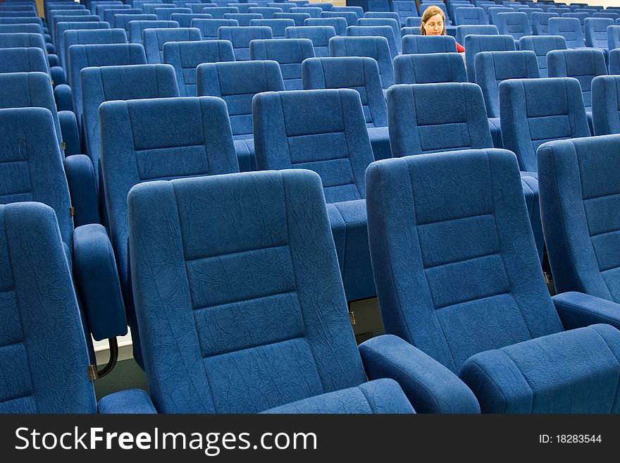 A womwn is sitting alone in an empty theater