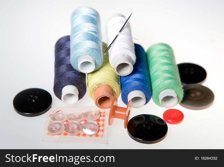 Thread sewing and needles with buttons on a white background