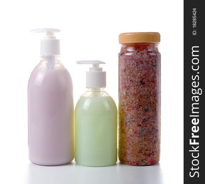 Bottles with liquid soap and sea salt on a white background