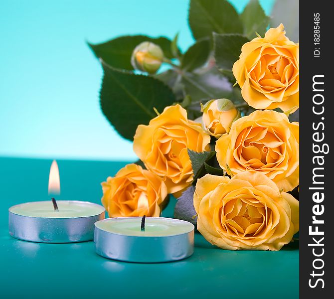 Beautiful yellow roses and candles on a green background