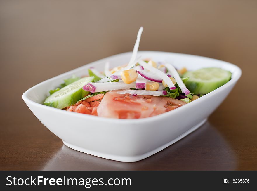 Photo of a plate with salad, on a wooden table.