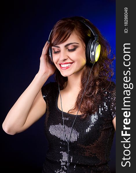 Beautiful young woman with Headphones listening music and smiling