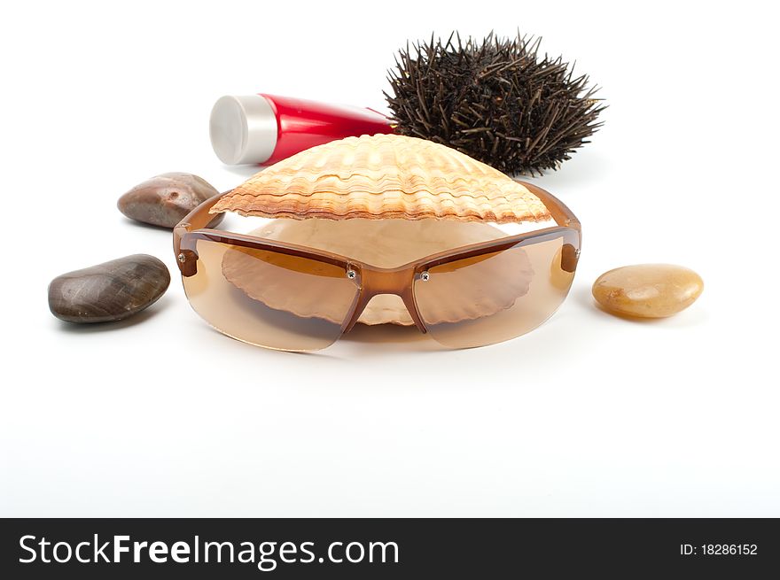 Sun glass on white background with seashell,stones, sea-urchin and sun block. Sun glass on white background with seashell,stones, sea-urchin and sun block