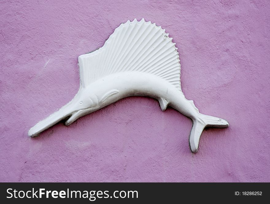 White swordfish against a pink stucco background