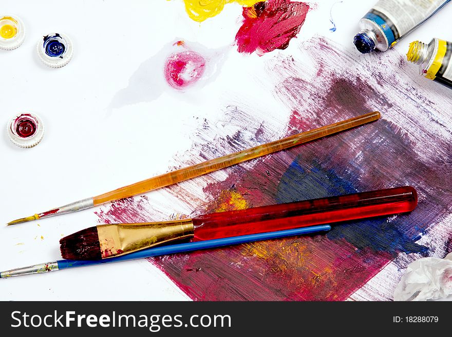 Paint and brushes set aside on a table work space. Paint and brushes set aside on a table work space.