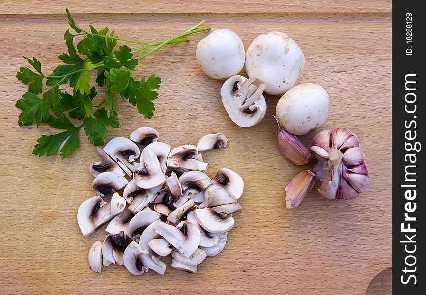 Mushrooms, whole and rolled, with garlic and parsley on wood. Mushrooms, whole and rolled, with garlic and parsley on wood