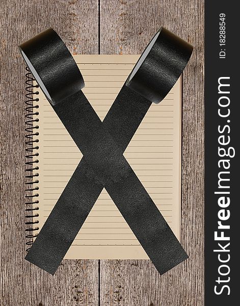 Vintage notebook stuck by black tape with wood background