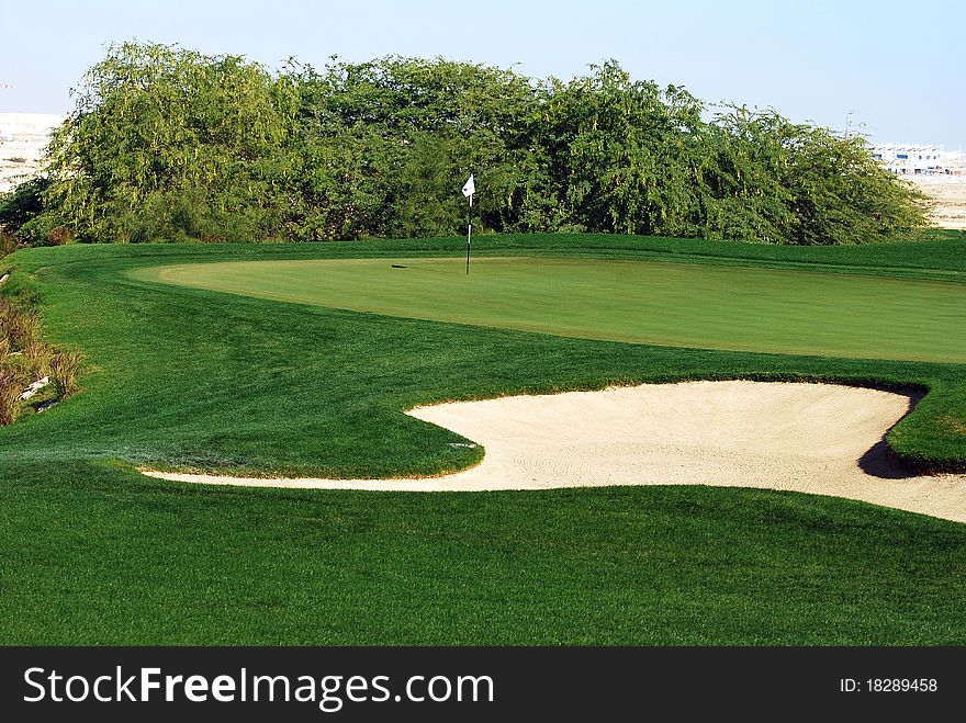 A well prepared green with a bunker in the foreground. A well prepared green with a bunker in the foreground