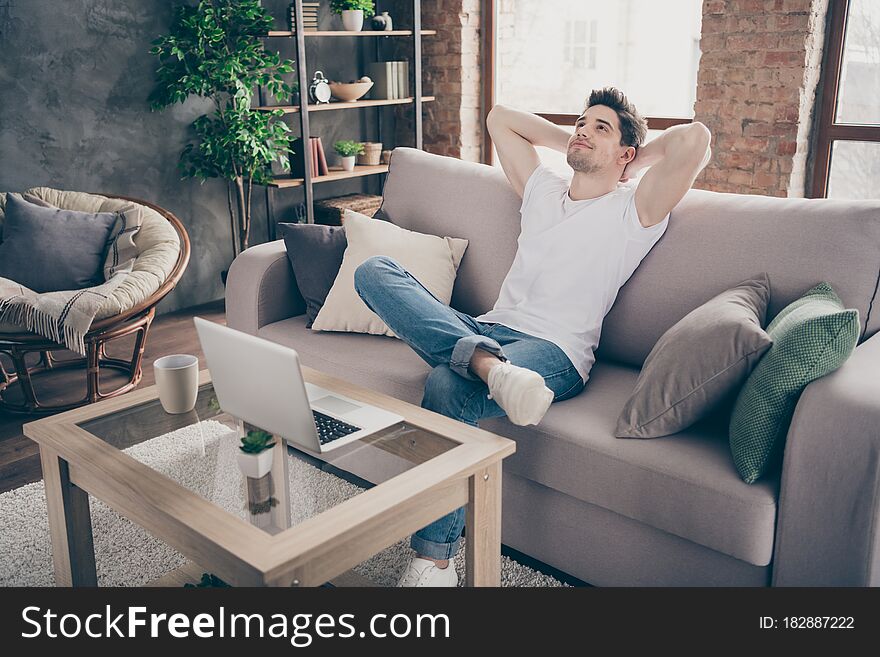 Portrait of his he nice attractive muscular dreamy guy sitting on divan resting, pause break working remotely at modern industrial loft interior style living-room indoors. Portrait of his he nice attractive muscular dreamy guy sitting on divan resting, pause break working remotely at modern industrial loft interior style living-room indoors