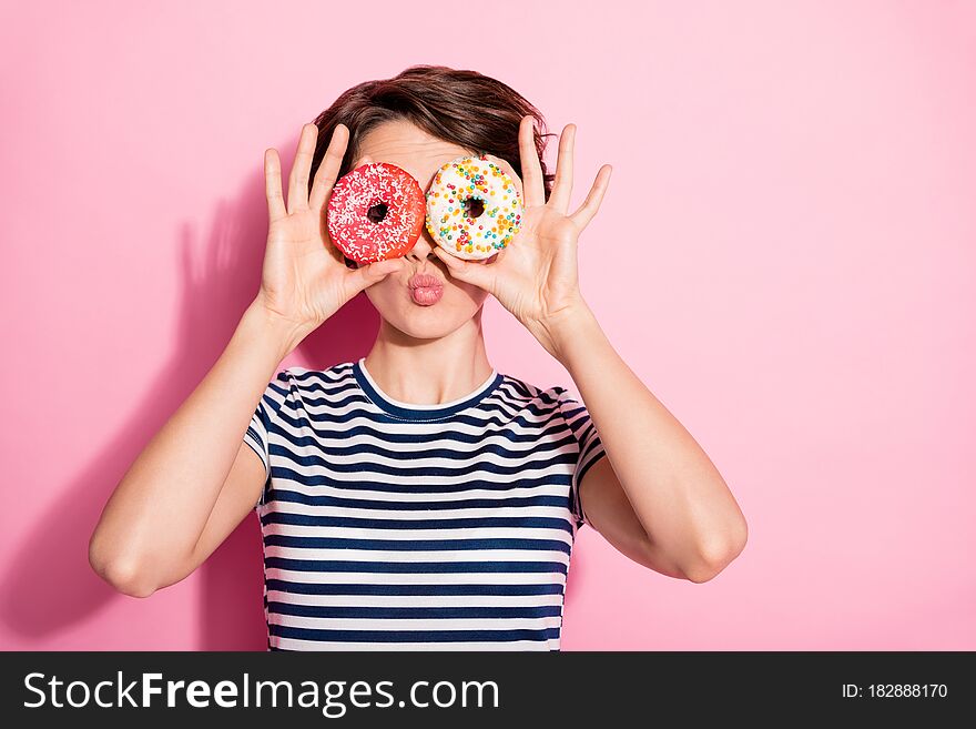Closeup photo of attractive funny lady hold hands two sweet baked, donuts like specs near eyes sending air kisses wear casual white blue t-shirt isolated pastel pink color background. Closeup photo of attractive funny lady hold hands two sweet baked, donuts like specs near eyes sending air kisses wear casual white blue t-shirt isolated pastel pink color background