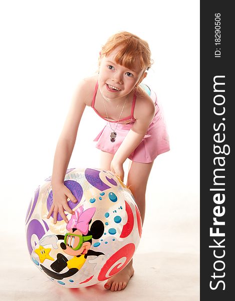 Cute little girl in pink swimsuit playing with a beach ball