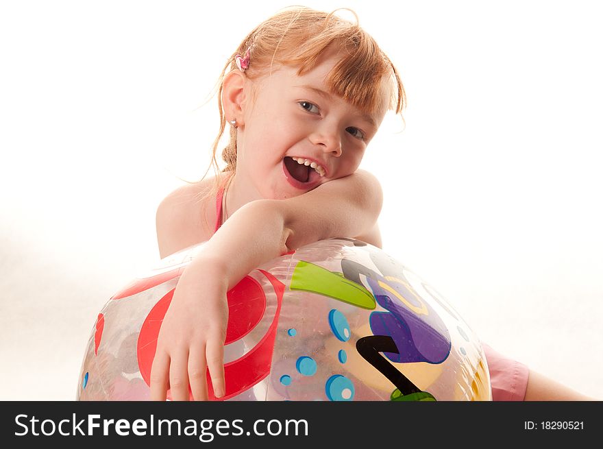 Cute little girl in pink swimsuit playing with a beach ball