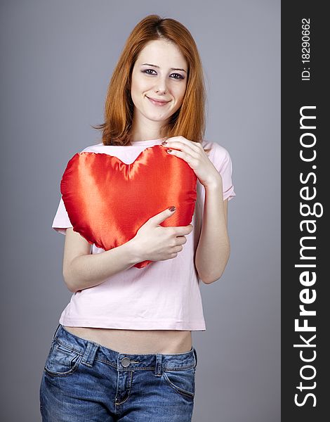 Beautiful red-haired girl with toy heart. Studio shot.