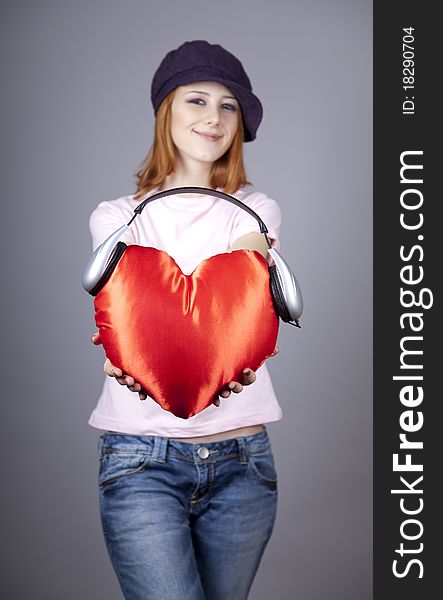 Beautiful red-haired girl with toy heart. Studio shot.