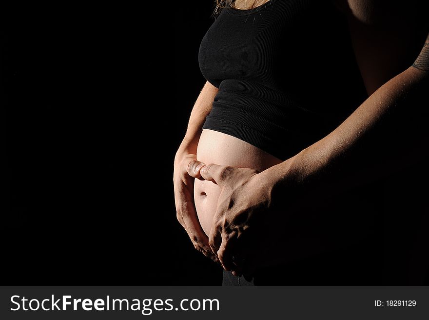 A man and a woman embracing a pregnant stomach. A man and a woman embracing a pregnant stomach