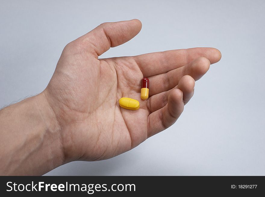 Hand with two pills, blue background