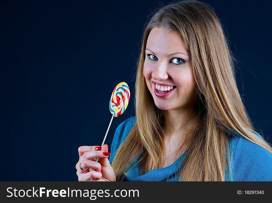 Beautiful girl holding a candy on a stick in his hand