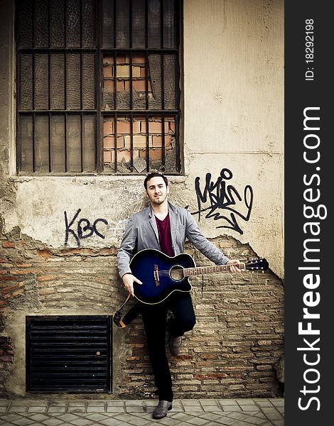 Young attractive street artist with his guitar.