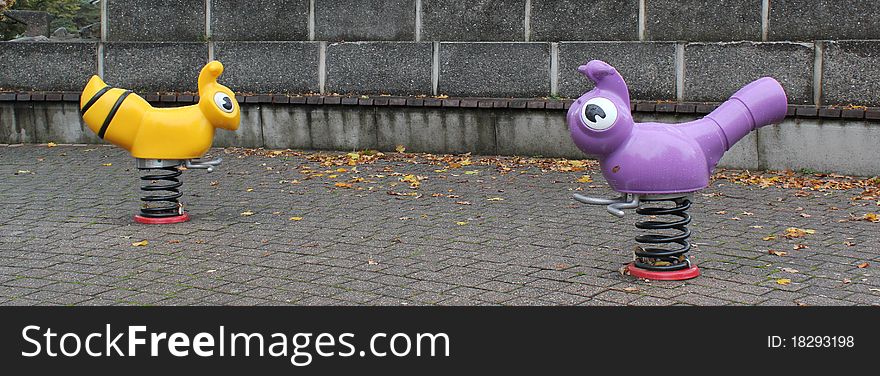 Playground for children with two plastic animals on springs by rainy autumn day