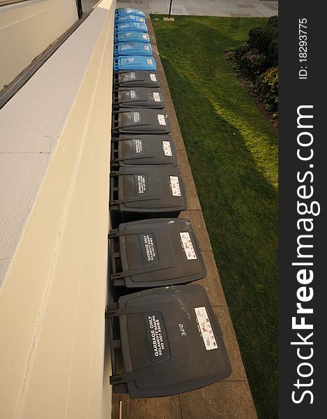 A row of recycling and garbage cans from above. A row of recycling and garbage cans from above.