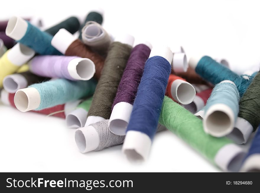 A pile of multicolored spools of thread on a white background