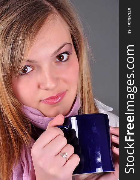 Beautiful blond woman woth tea cup on grey background