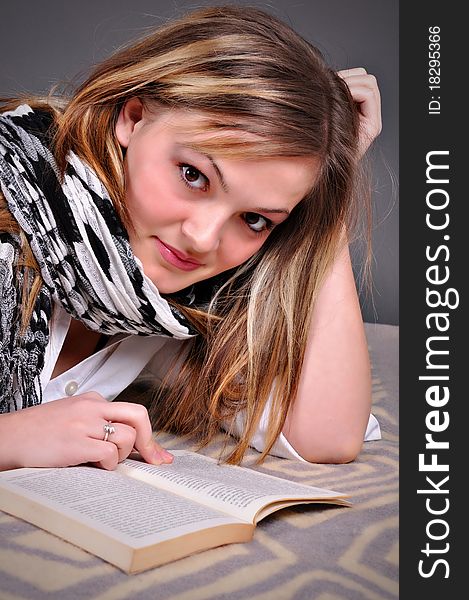 Young woman with book on grey background