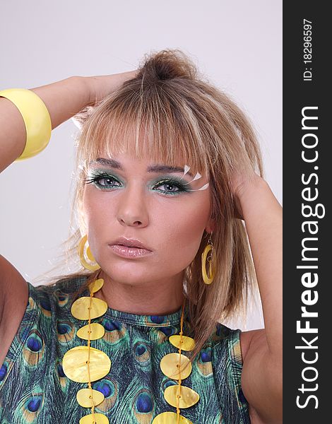 Blond fashion model in studio with green makeup and fake eyelashes
