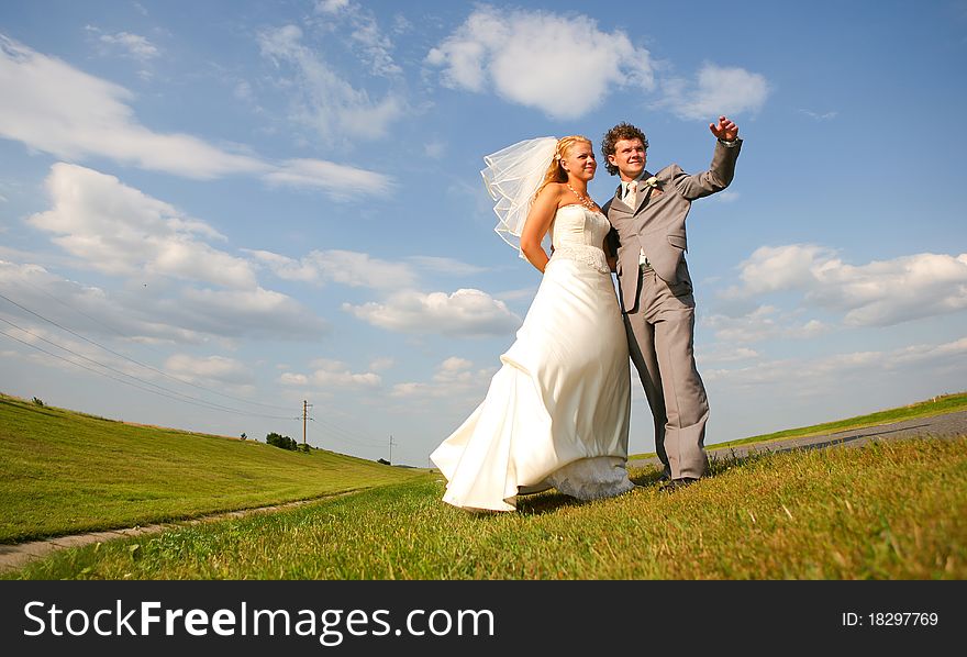 Bride and groom walking in a field. Bride and groom walking in a field
