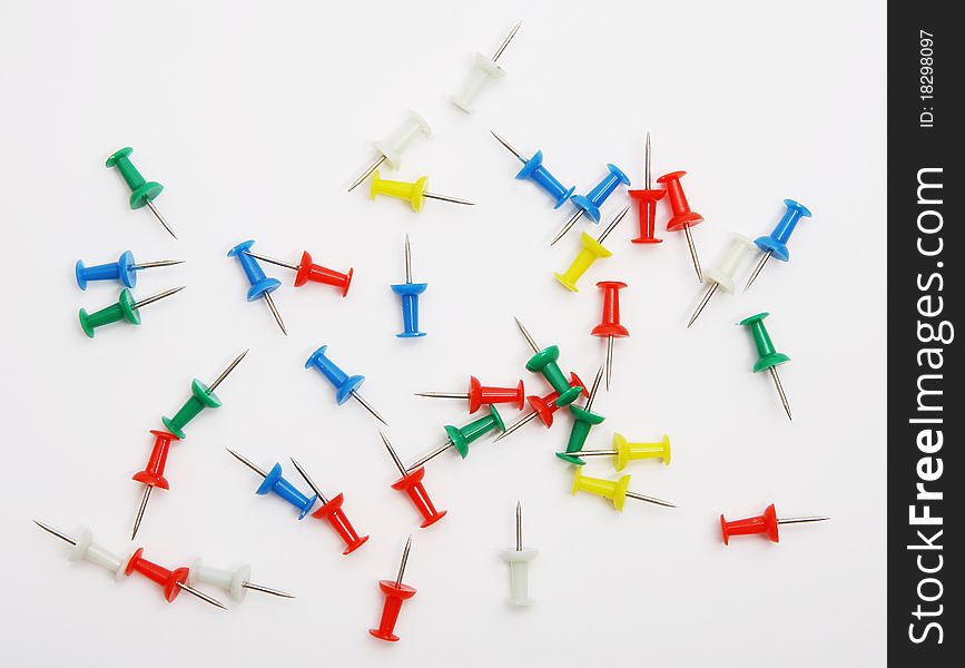 Colored push pins from above on a white background