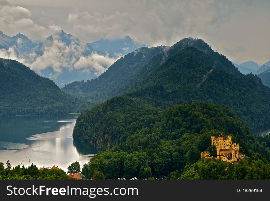 View of a bavarian castle amongst the alps with an alpine lake as well.
