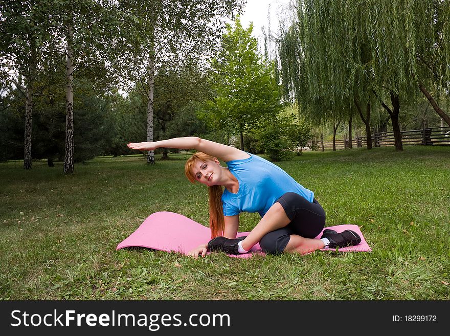 Young woman engages in fitness on beautiful lawn in a birchwood