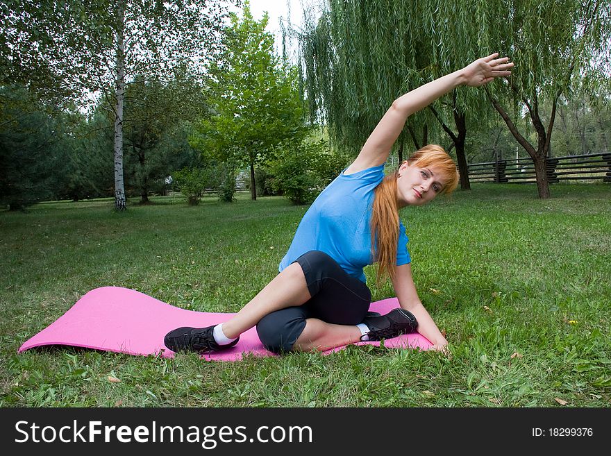 Young woman engages in fitness on beautiful lawn in a birchwood