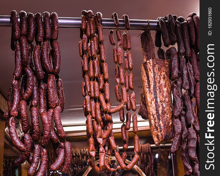 Many homemade German mix of meat specialties, speck ham sausages pile or stack on counter top, for sale, during food festival, outdoor outside marketplace, spicy and tasty fresh specialty for sale