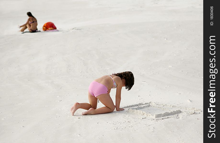 A little girl in a pink bathing suit building a sand castle at the beach in Florida. A little girl in a pink bathing suit building a sand castle at the beach in Florida.