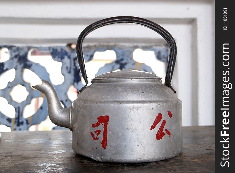 Old metal teapot with Chinese text painted in red.