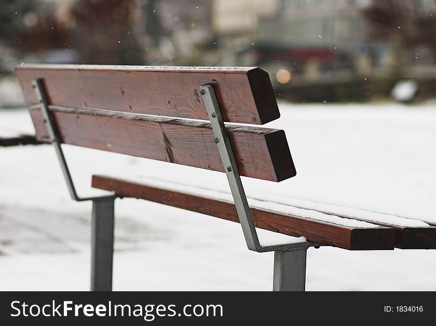 Abandoned park bench at winter while snowing. Shallow depth of field. Abandoned park bench at winter while snowing. Shallow depth of field